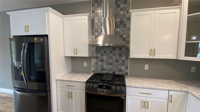 kitchen featuring white cabinetry, stainless steel fridge, wall chimney exhaust hood, and black range with gas cooktop