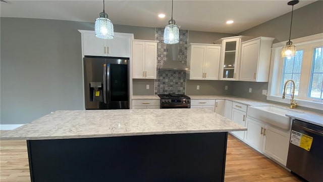 kitchen with a center island, white cabinets, sink, decorative light fixtures, and stainless steel appliances