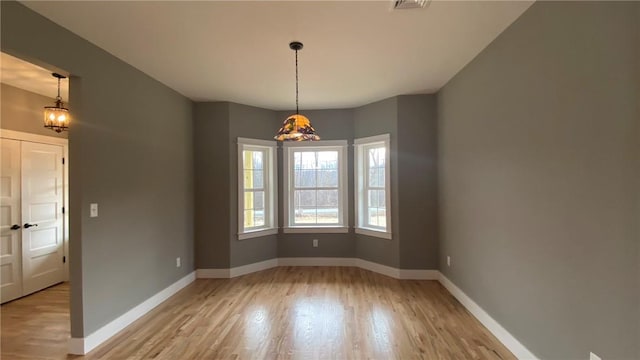 unfurnished room with light hardwood / wood-style flooring and an inviting chandelier