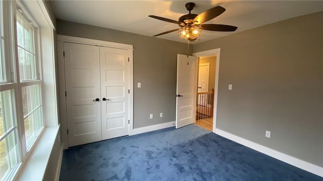 unfurnished bedroom featuring ceiling fan, a closet, and dark carpet