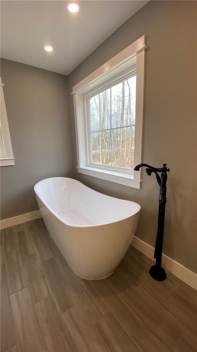 bathroom with a bath and hardwood / wood-style floors