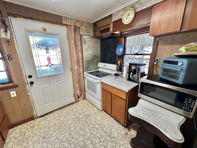 kitchen with white range with electric stovetop, wood walls, and crown molding