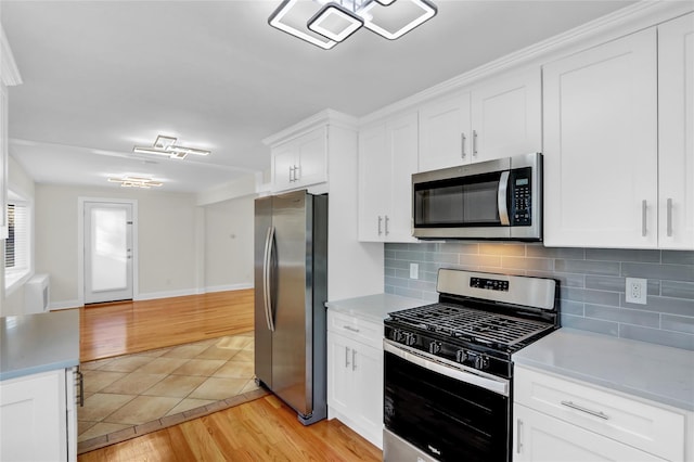 kitchen featuring white cabinets, decorative backsplash, stainless steel appliances, and light hardwood / wood-style flooring