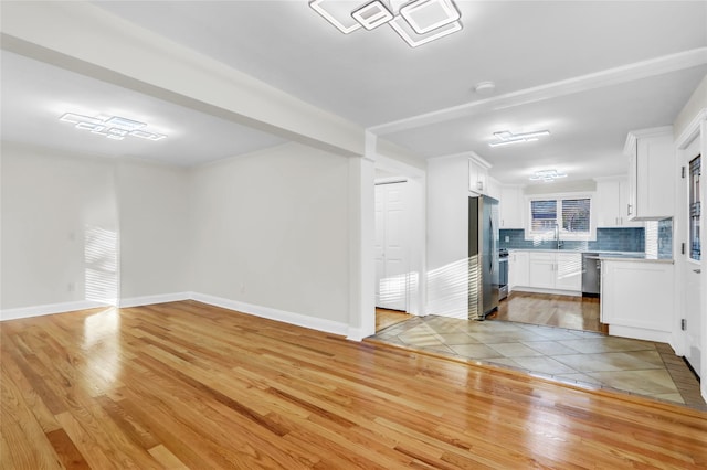 interior space featuring white cabinets, decorative backsplash, light hardwood / wood-style floors, and stainless steel appliances