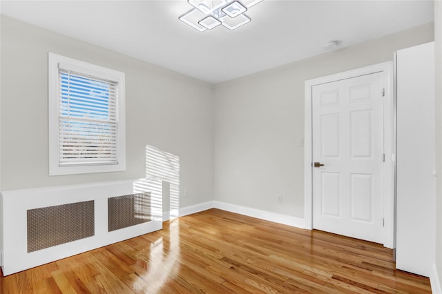 unfurnished living room featuring radiator and wood-type flooring