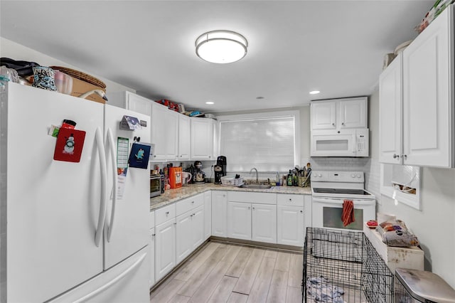 kitchen featuring sink, white cabinets, white appliances, and light wood-type flooring