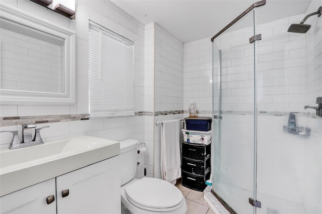 bathroom with walk in shower, tile patterned flooring, toilet, vanity, and tile walls