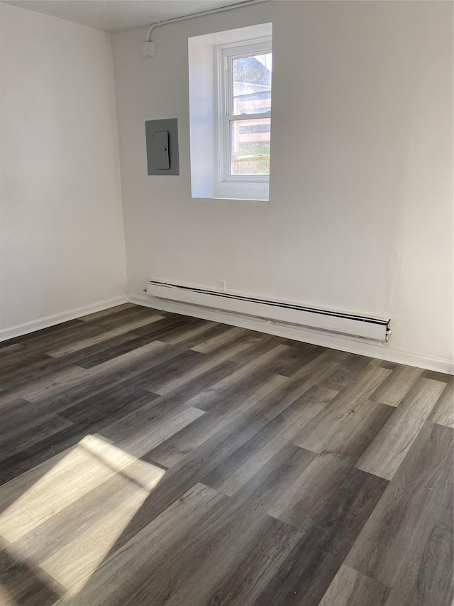 empty room featuring dark hardwood / wood-style floors, electric panel, and a baseboard radiator