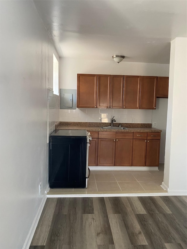 kitchen with wood-type flooring, stove, electric panel, and sink