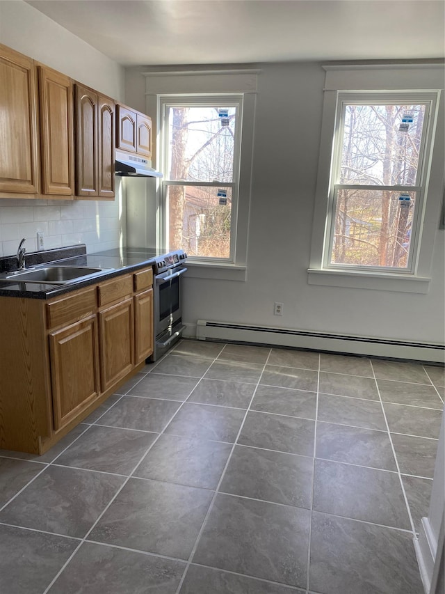 kitchen with decorative backsplash, baseboard heating, a healthy amount of sunlight, and sink