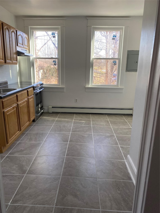 kitchen with a healthy amount of sunlight, dark tile patterned floors, sink, and a baseboard heating unit