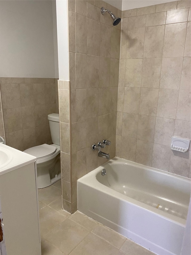 full bathroom with tile patterned floors, vanity, tiled shower / bath combo, tile walls, and toilet