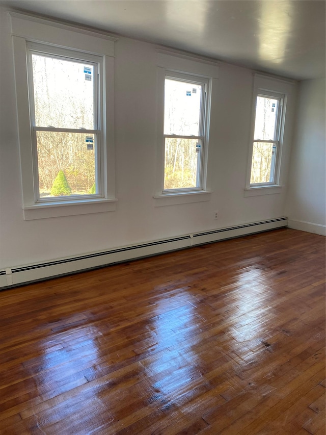 unfurnished room featuring baseboard heating and dark wood-type flooring