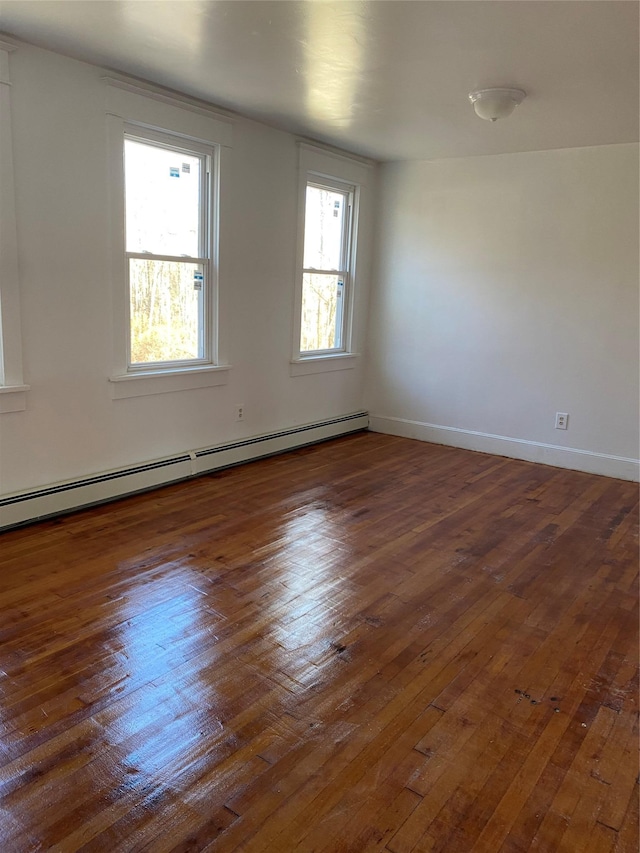 spare room featuring dark hardwood / wood-style flooring, plenty of natural light, and a baseboard heating unit