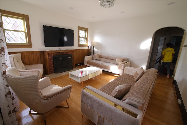 living room featuring wood-type flooring, a brick fireplace, and plenty of natural light