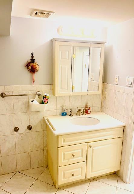 bathroom with tile patterned flooring, vanity, and tile walls