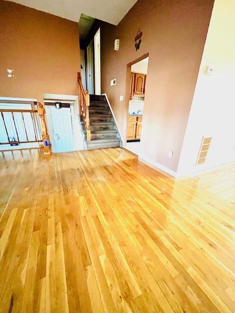 unfurnished living room featuring a towering ceiling and light hardwood / wood-style floors