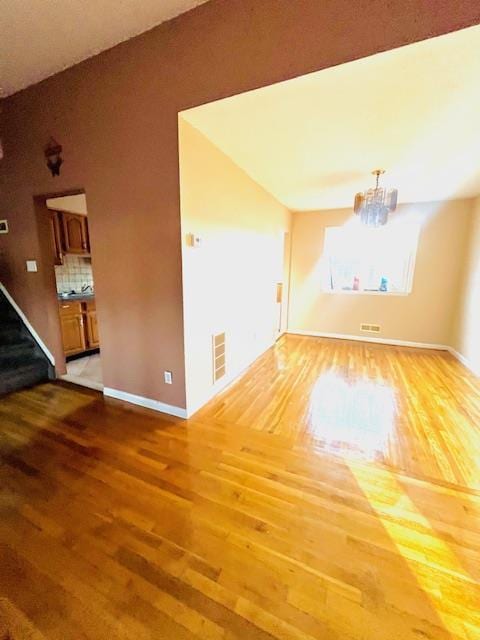 unfurnished living room with hardwood / wood-style floors and a chandelier