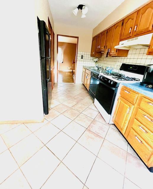 kitchen featuring black appliances, light tile patterned floors, sink, and tasteful backsplash