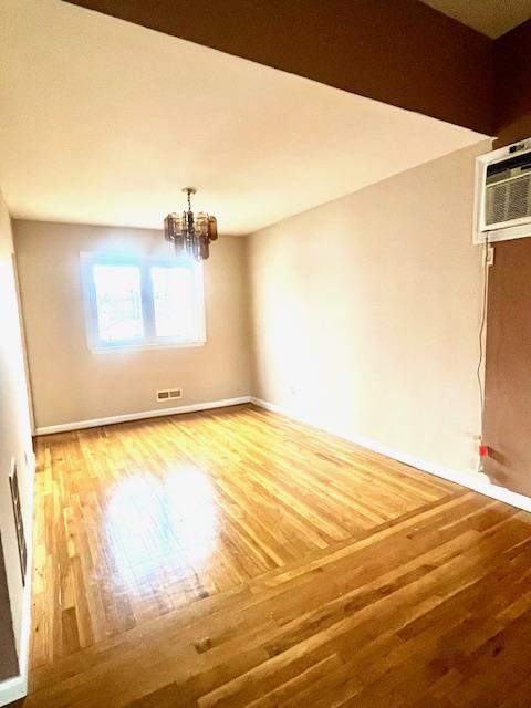 interior space featuring an AC wall unit, hardwood / wood-style flooring, and an inviting chandelier