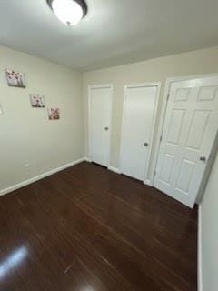 unfurnished bedroom featuring dark hardwood / wood-style floors and two closets