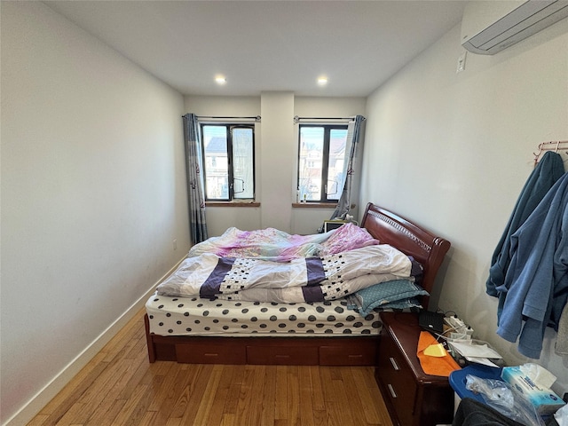 bedroom with wood-type flooring and a wall unit AC