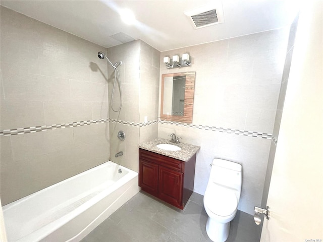 full bathroom featuring tile walls, tile patterned flooring, vanity, toilet, and tiled shower / bath