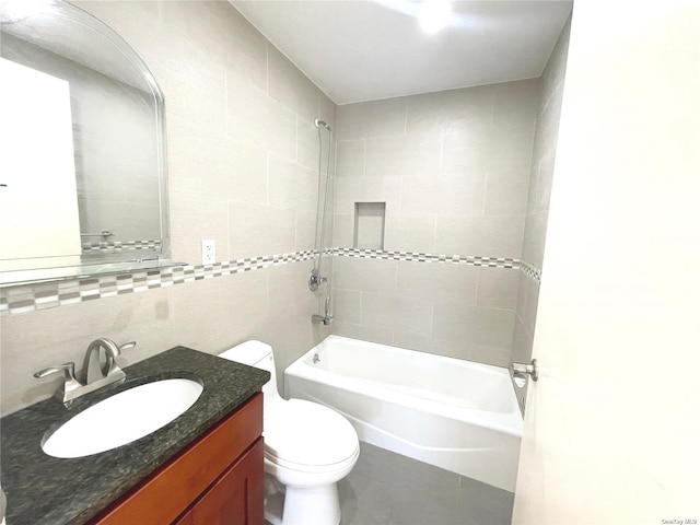 full bathroom featuring tiled shower / bath, tasteful backsplash, tile walls, vanity, and toilet