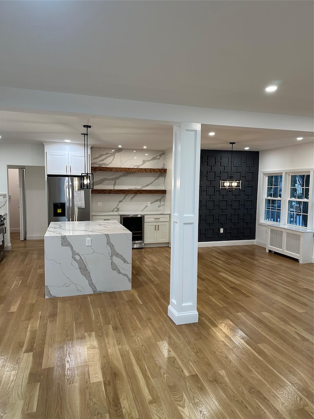 kitchen featuring radiator, stainless steel fridge with ice dispenser, white cabinets, and decorative light fixtures