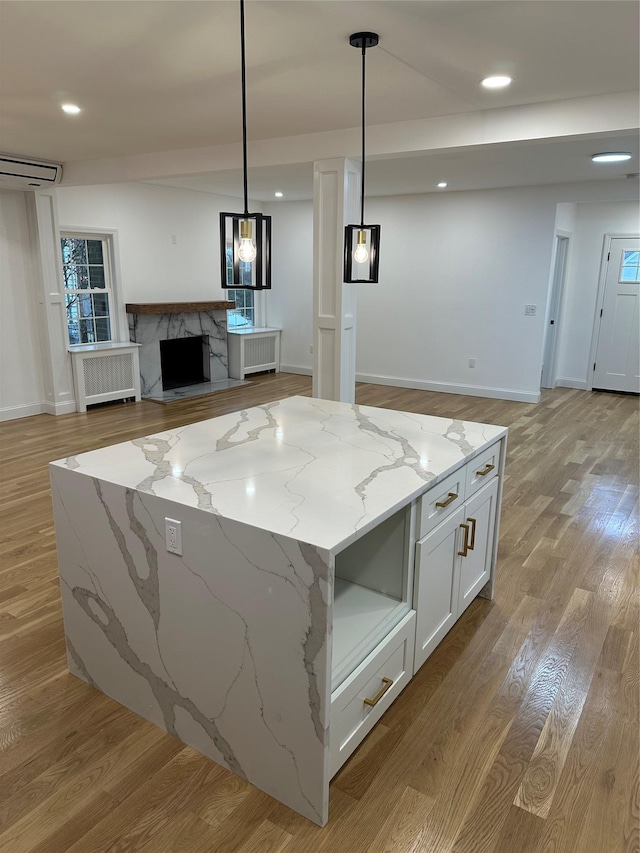 kitchen with light stone counters, radiator, pendant lighting, a premium fireplace, and white cabinetry