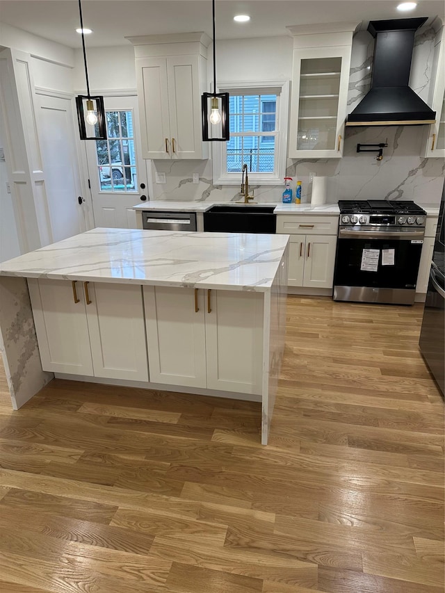 kitchen featuring white cabinetry, light stone countertops, premium range hood, pendant lighting, and appliances with stainless steel finishes