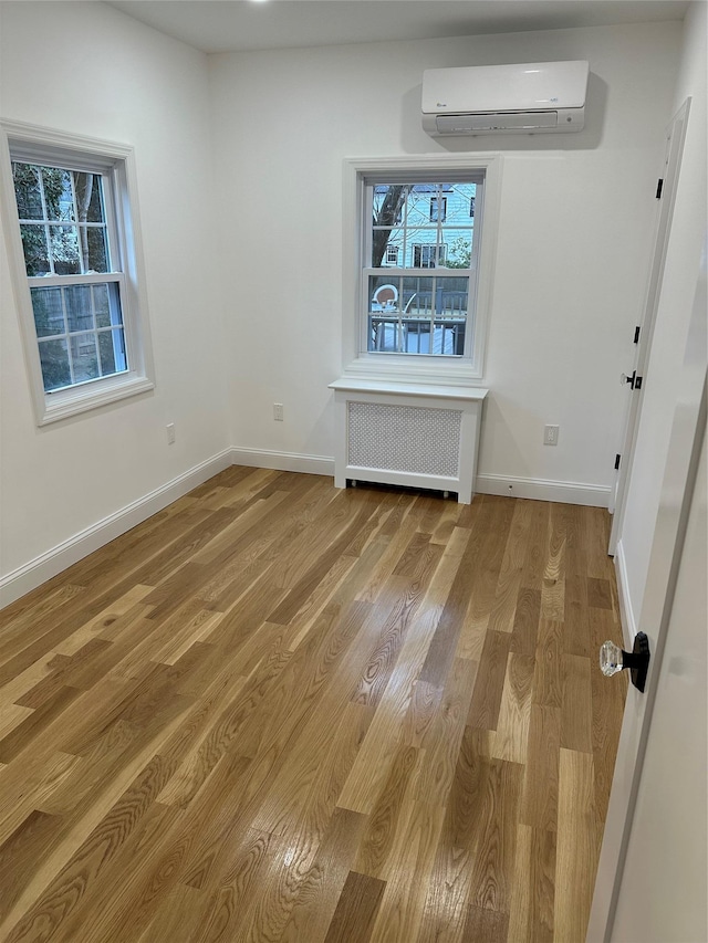 unfurnished dining area featuring a wall mounted air conditioner, plenty of natural light, light wood-type flooring, and radiator