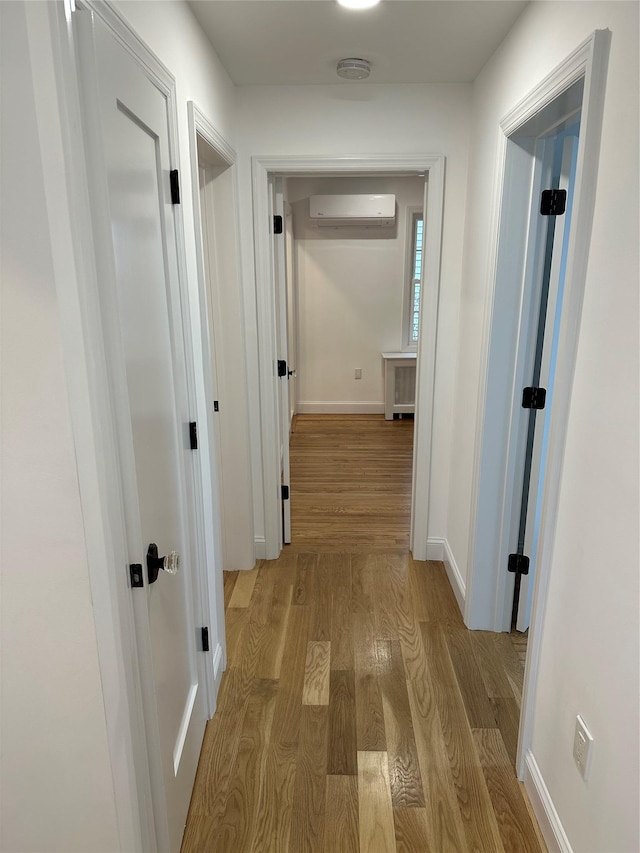 hallway featuring an AC wall unit and light hardwood / wood-style flooring