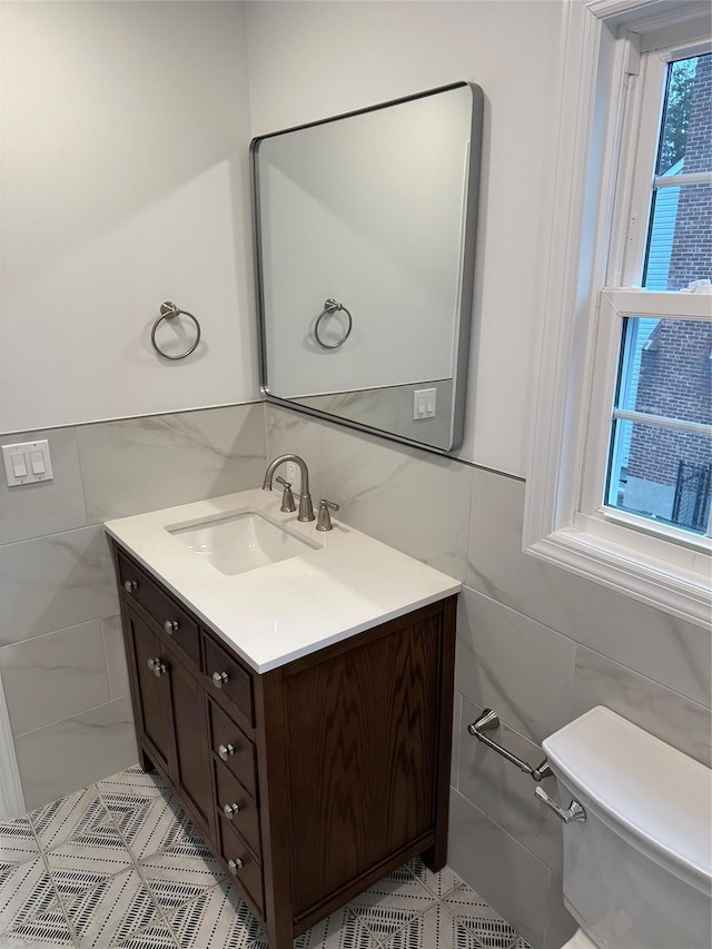 bathroom with vanity, toilet, and tile walls