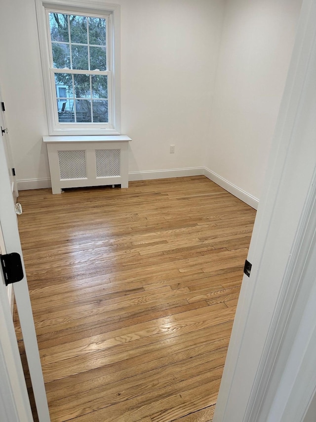 spare room with radiator heating unit and light wood-type flooring