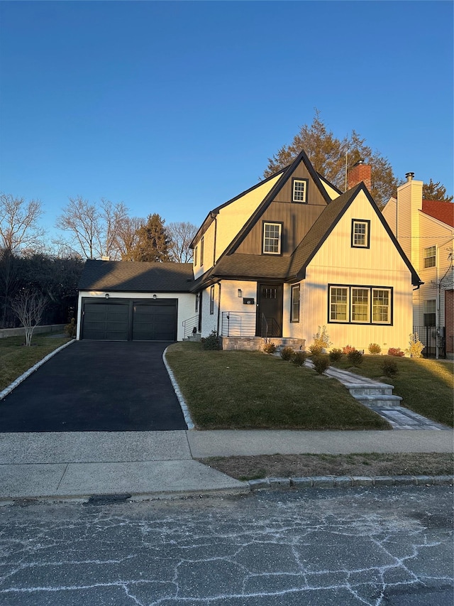 view of front of house featuring a garage, aphalt driveway, and a front yard