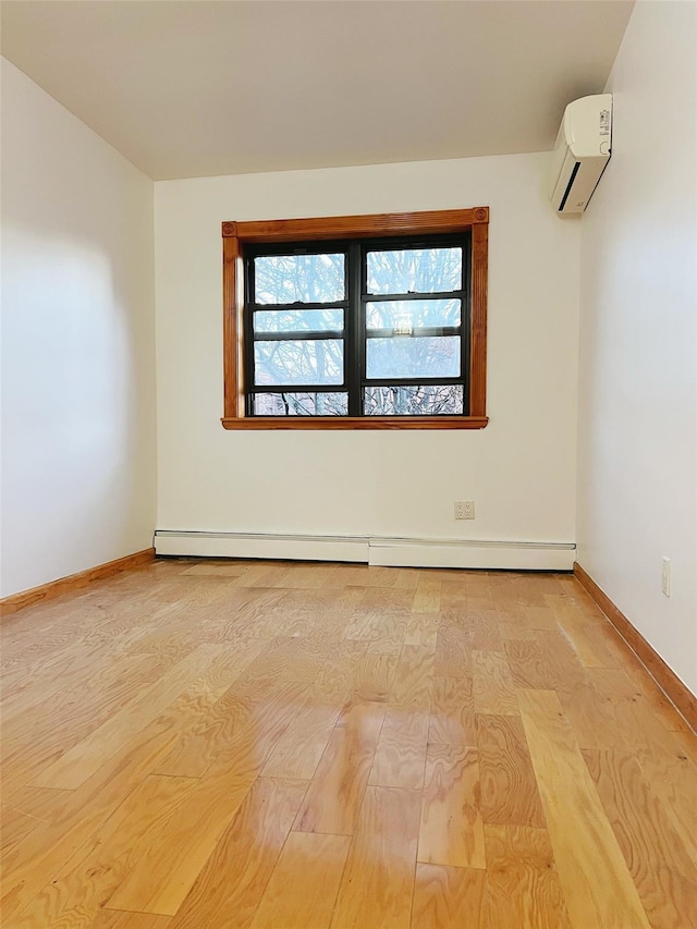 empty room featuring light hardwood / wood-style flooring, an AC wall unit, and a baseboard heating unit