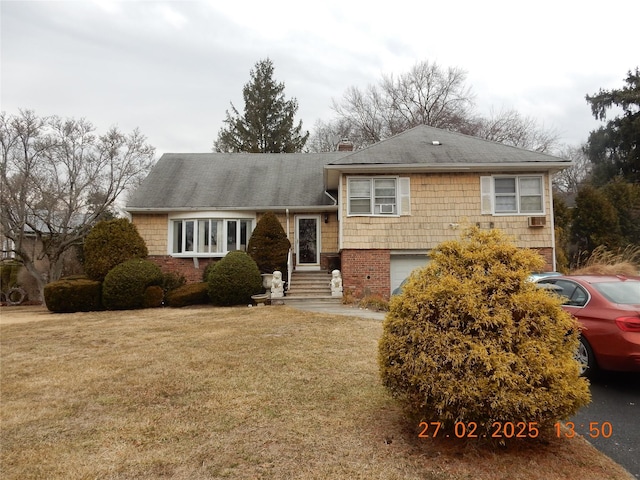 split level home with an attached garage, a chimney, a front lawn, and brick siding