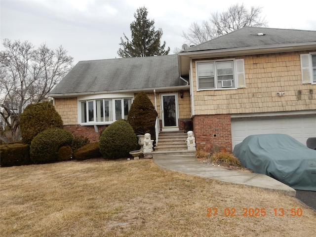 split level home with a garage, a front yard, and brick siding