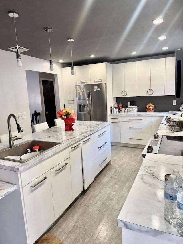 kitchen with stainless steel fridge with ice dispenser, sink, a large island, and decorative light fixtures