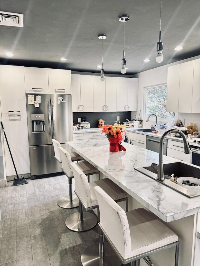 kitchen featuring white cabinetry, hanging light fixtures, a kitchen breakfast bar, stainless steel fridge with ice dispenser, and light hardwood / wood-style floors