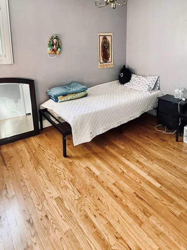 bedroom featuring light wood-type flooring and an inviting chandelier