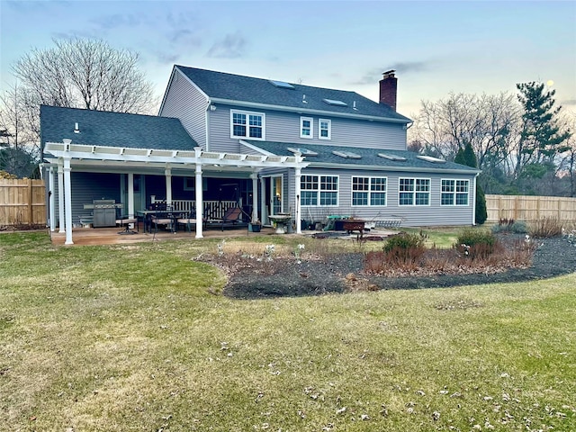 rear view of house featuring a pergola, a lawn, and a patio