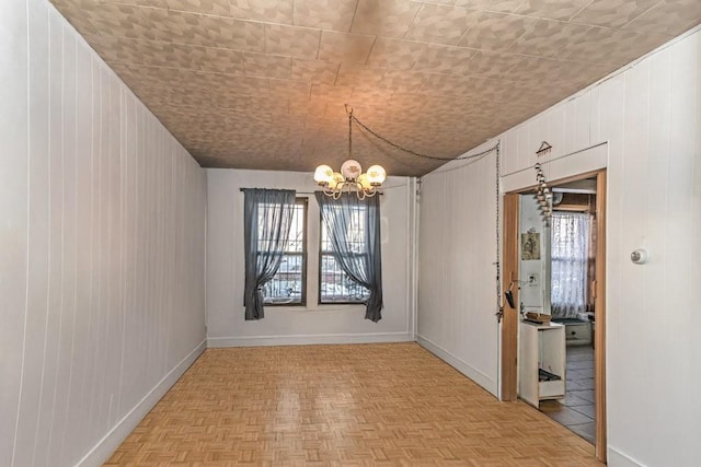 unfurnished dining area with a chandelier, light parquet flooring, and wooden walls