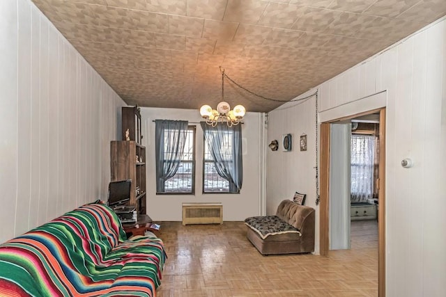 sitting room featuring a healthy amount of sunlight, light parquet flooring, wood walls, and a notable chandelier