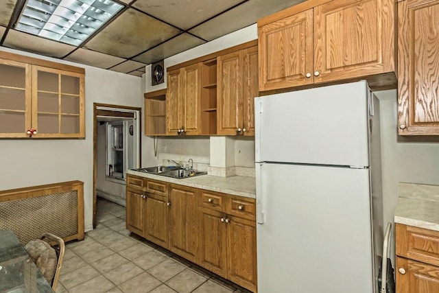 kitchen featuring sink, light tile patterned flooring, radiator, a paneled ceiling, and white refrigerator