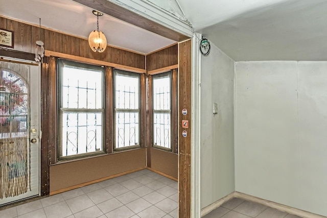 tiled entryway with lofted ceiling and wood walls