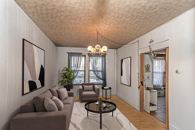 living room featuring light parquet flooring, wooden walls, and a notable chandelier