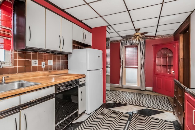 kitchen featuring tasteful backsplash, a drop ceiling, ceiling fan, white refrigerator, and dishwasher