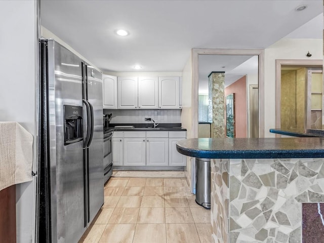 kitchen featuring kitchen peninsula, appliances with stainless steel finishes, tasteful backsplash, and white cabinetry